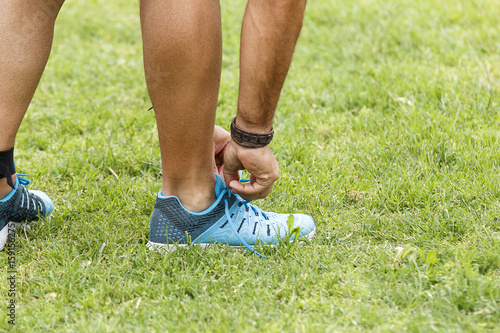 Chico depilado atándose la zapatilla de deporte antes de correr