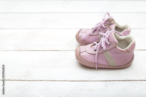 Pink little shoes for a girl on a white wooden background