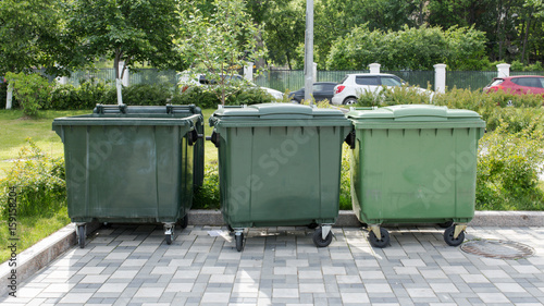 Opened green plastic recycling container at the sunny city street