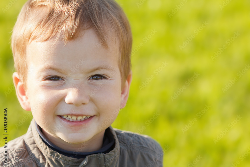 Portrait redhead child boy smiling on background of green grass Portrait redhead child boy smiling on background of green grass