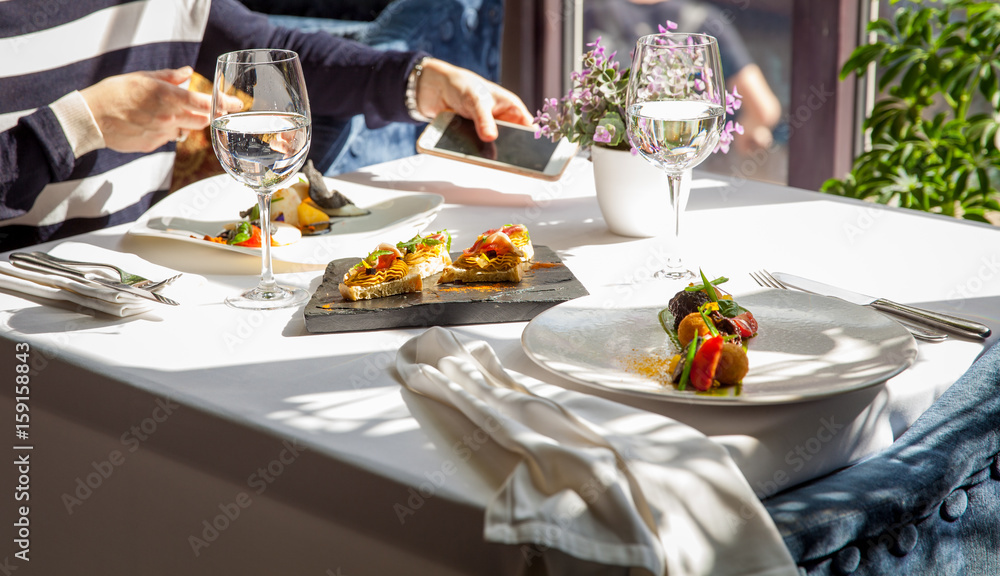 Young woman in a restaurant at a table with a mobile phone. Restaurant food concept.