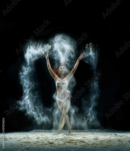 Fototapeta Naklejka Na Ścianę i Meble -  Pretty girl in cloud of white dust studio portrait