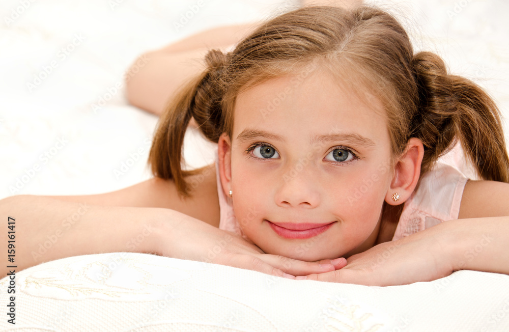 Adorable smiling little girl is resting on a bed Adorable smiling little girl is resting on a bed