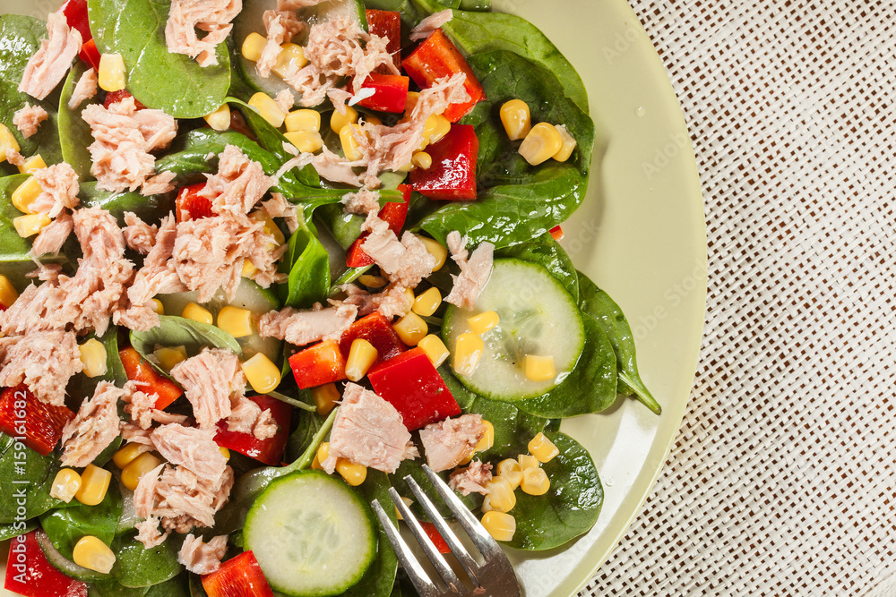 Fresh spinach salad with tuna, cucumber, corn, and red paprika o