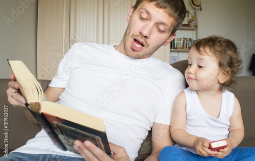 Dad is reading a book with a child. Young father. Father's Day