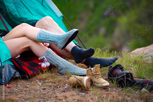 Feet of young man and woman. Couple lying in a tent. Camping, travel, tourism, hike and people concept.