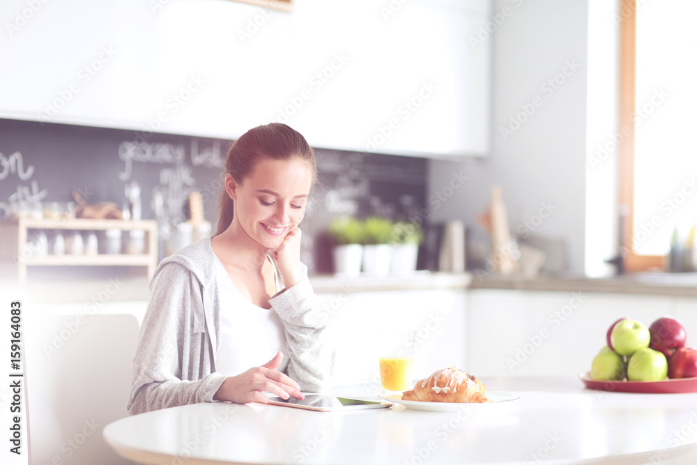 Young woman with orange juice and tablet in kitchen. Young woman with orange juice and tablet in kitchen.