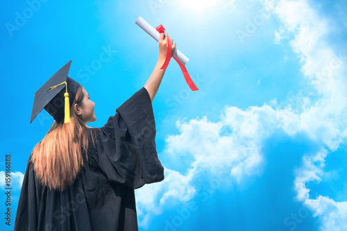 happy graduate showing certificated in hand with sky background photo