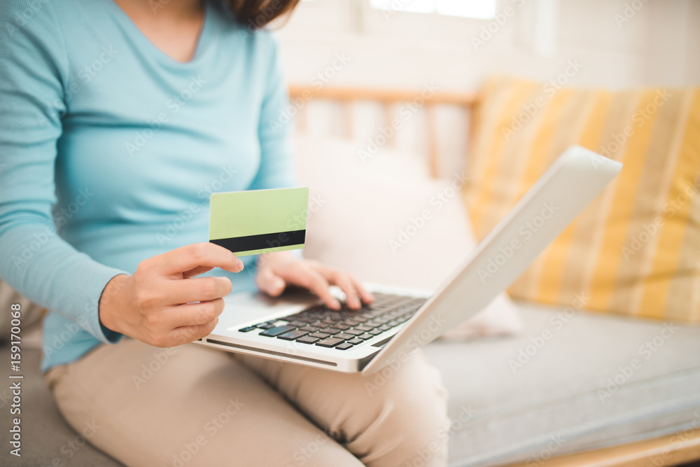 Fototapeta premium Online shopping concept. Young asian woman holding credit card and using laptop computer.
