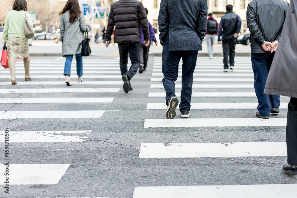 People are walking on a crosswalk on a city street. People are walking on a crosswalk on a city street.