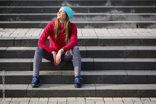 Sport beautiful young woman sitting on the steps, urban style, sports, healthy lifestyle