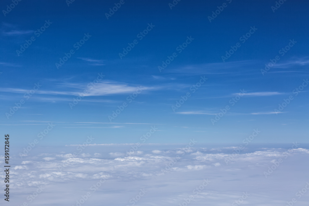 Clouds background with blue sky from above. View from airplane window