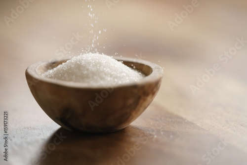 sugar pour in wood bowl on wooden table, with copy space