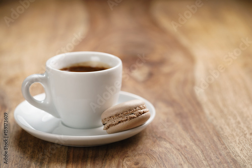 cup of fresh espresso with macaron on wood table with copy space