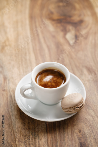 cup of fresh espresso with macaron on wood table with copy space