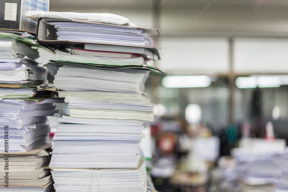 Many files and piles of paper lay on a messy office table. Many files and piles of paper lay on a messy office table.