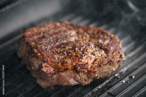 beef rib eye steak on grill pan closeup, shallow focus