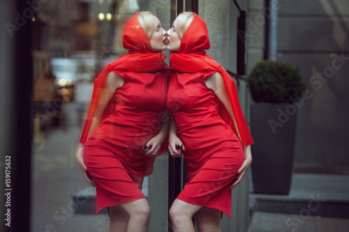 Foto Woman kisses her reflection in the shop window, she loves herself much