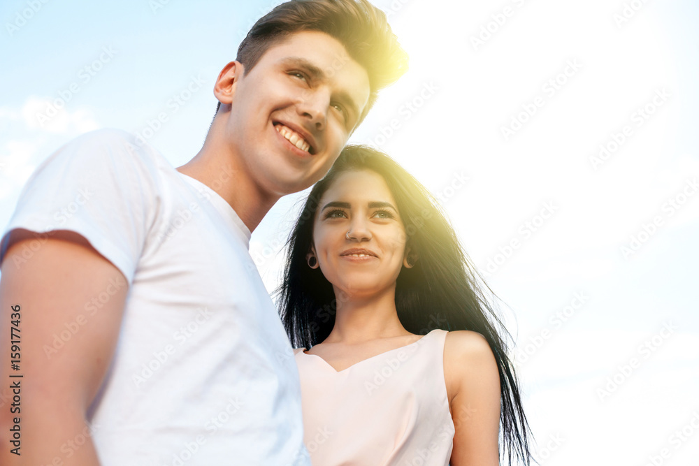 The guy and the girl with the perfect smile, laugh and look forward in the background of a Sunny day. Beautiful young couple during a romantic date. The guy and the girl with the perfect smile, laugh and look forward in the background of a Sunny day. Beautiful young couple during a romantic date.
