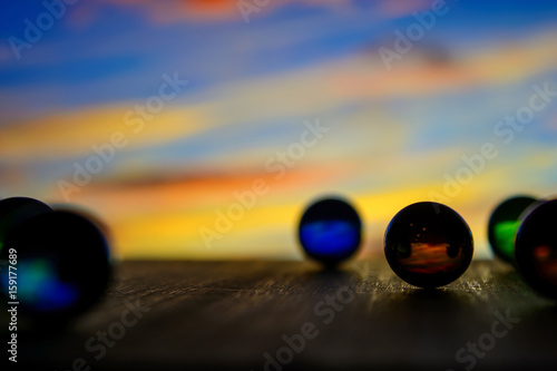 Photo of many glass balls on wooden board on blurred background