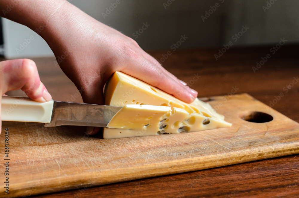 Slicing cheese on a wooden board. Slicing cheese on a wooden board.