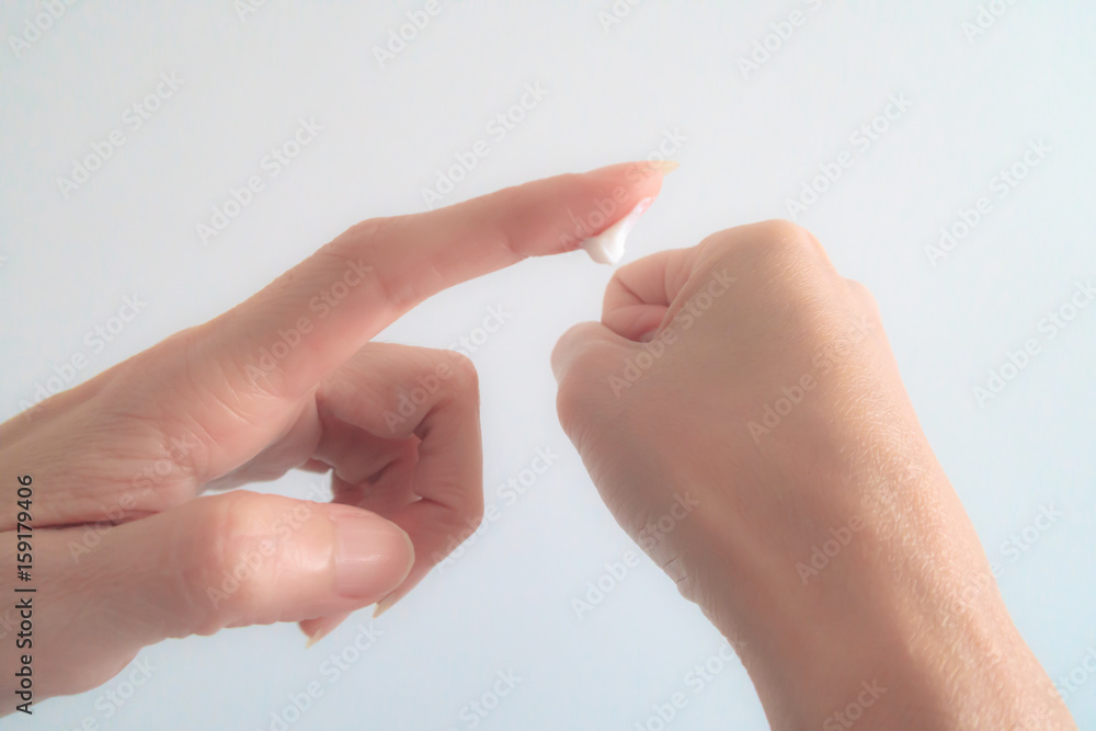Naklejka premium Close-Up Woman Hand Applying Moisturizing cream on White Background