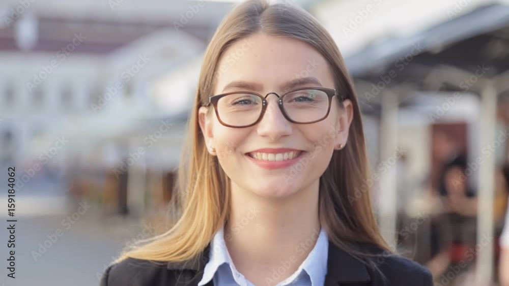 Portrait of smiling young professional woman in eyeglasses standing in city on sunny day. Portrait of smiling young professional woman in eyeglasses standing in city on sunny day.