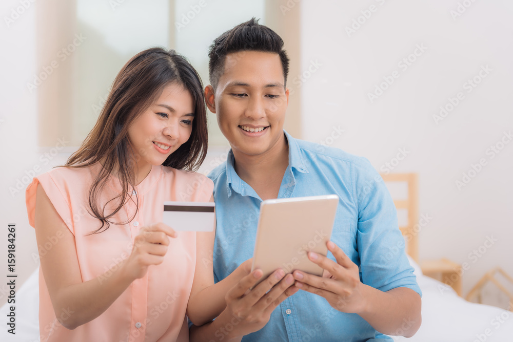 Happy Asian couple using tablet and credit card for online shopping Happy Asian couple using tablet and credit card for online shopping