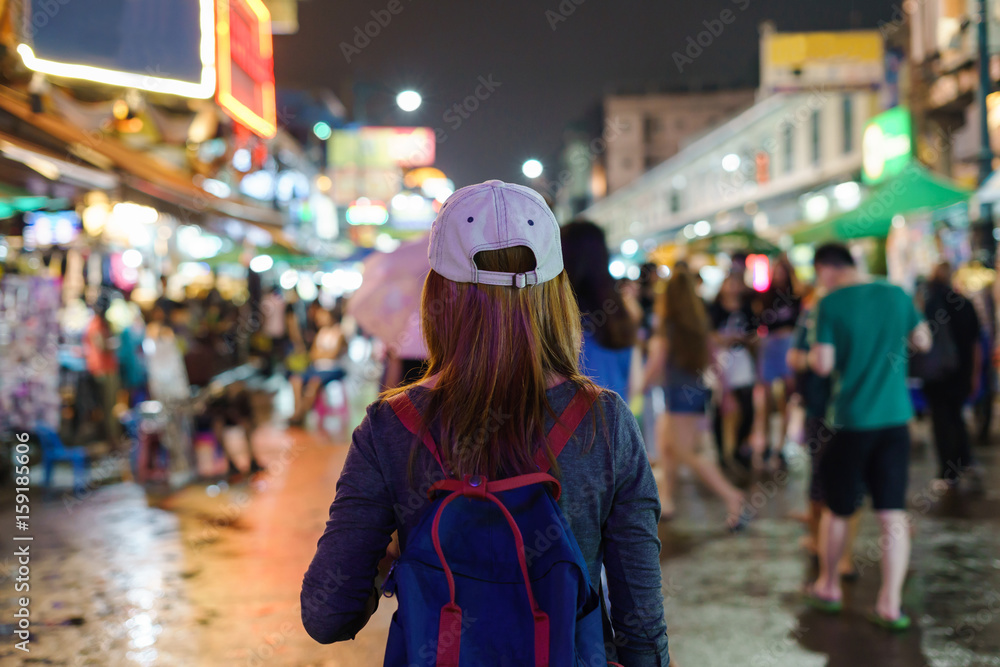 Naklejka premium young woman traveler walking in the Khao San road at night