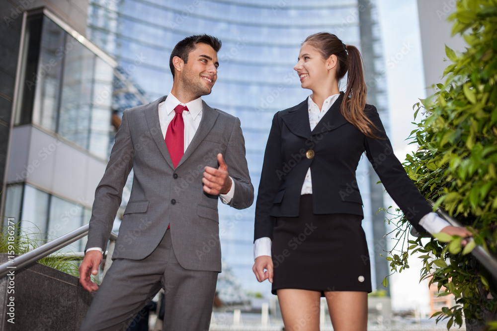 Business people talking while walking down the stairs after work Business people talking while walking down the stairs after work