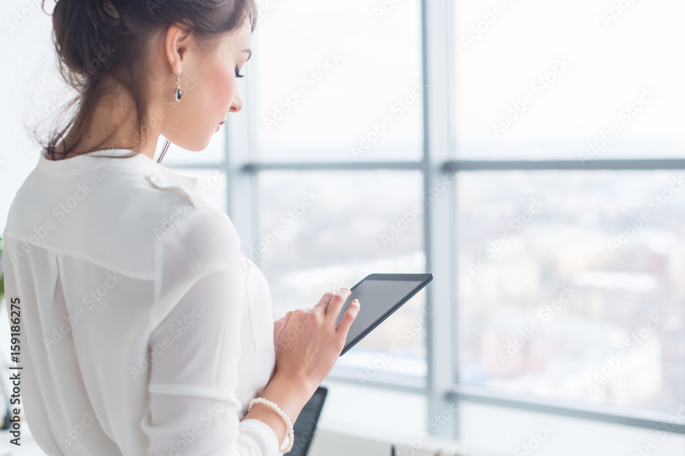 Close-up side view portrait of an employee texting, sending and reading messages during her break at the workplace. Close-up side view portrait of an employee texting, sending and reading messages during her break at the workplace.