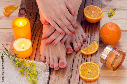 orange manicure around oranges and candles on a wooden background