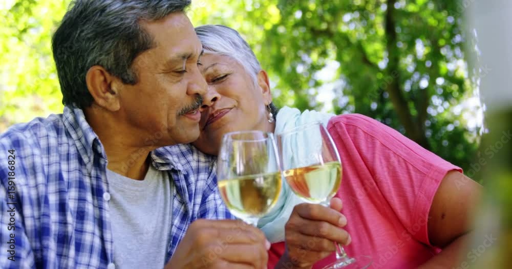 Senior couple kissing while drinking wine Senior couple kissing while drinking wine