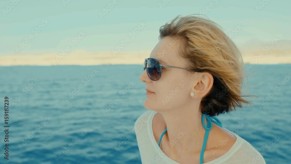 Profile closeup of a woman enjoying trip on yacht with hair fluttering on wind, looking forward Profile closeup of a woman enjoying trip on yacht with hair fluttering on wind, looking forward