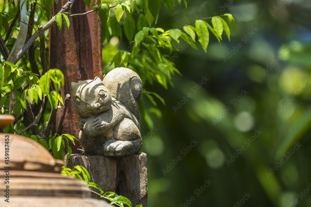 Obraz premium Squirrel stucco doll in the garden with green bokeh background.