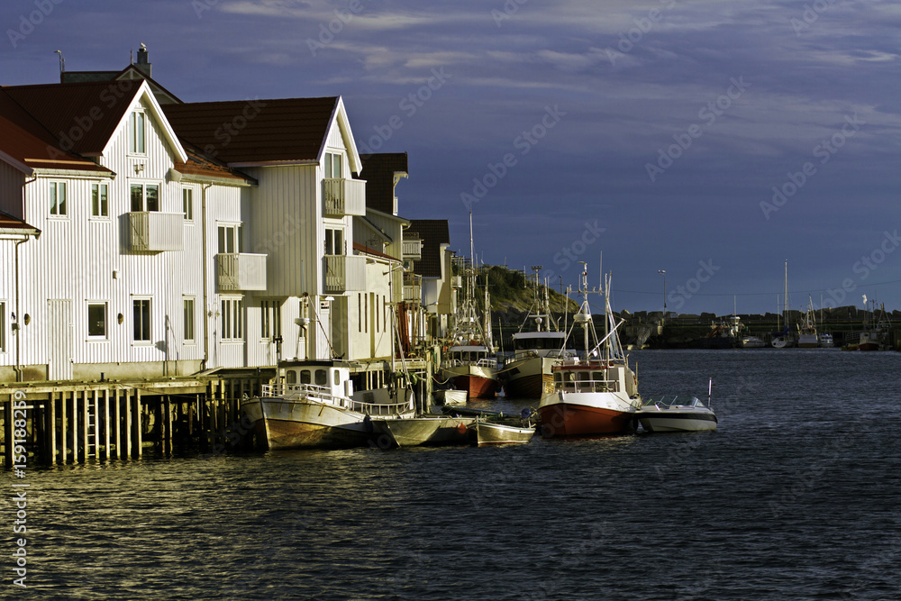 Boats, dock and houses in the harbor of Henningsfaer, Norway.