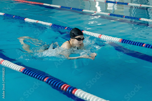 Canvas Print Young woman in goggles and cap swimming breaststroke stroke style in the blue wa