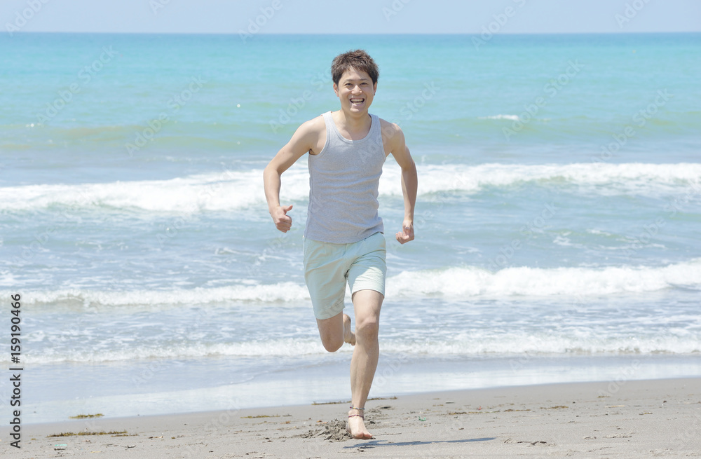 ビーチを走る若い男性