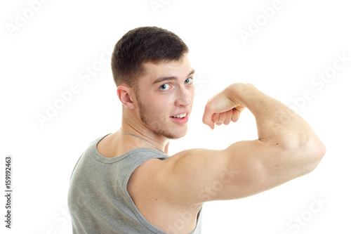 Young sports man showing his biceps and looking at the camera