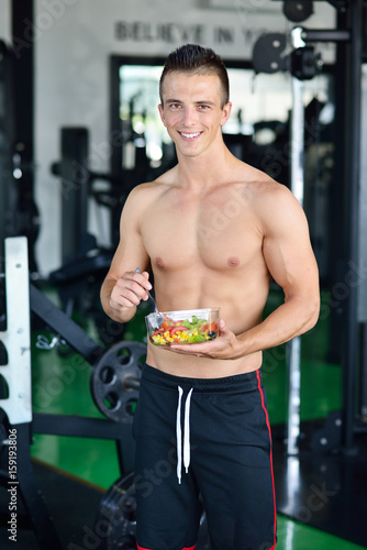 Powerful athletic man with great physique eating a healthy salad.