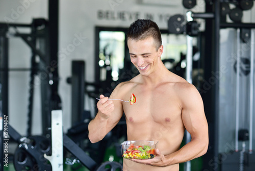 Powerful athletic man with great physique eating a healthy salad.