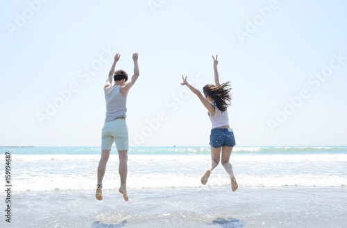 ビーチでジャンプする若いカップル