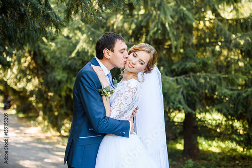 Bride and groom in a park kissing. couple newlyweds bride and groom at a wedding in nature green forest are kissing photo. Wedding Couple © Nestyda
