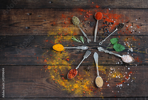 colorful spices in vintage silver spoons on rustic wooden background. photo