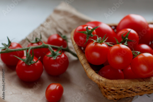 close-up of organic cherry tomatoes in a wicker basket on white background, selective focus