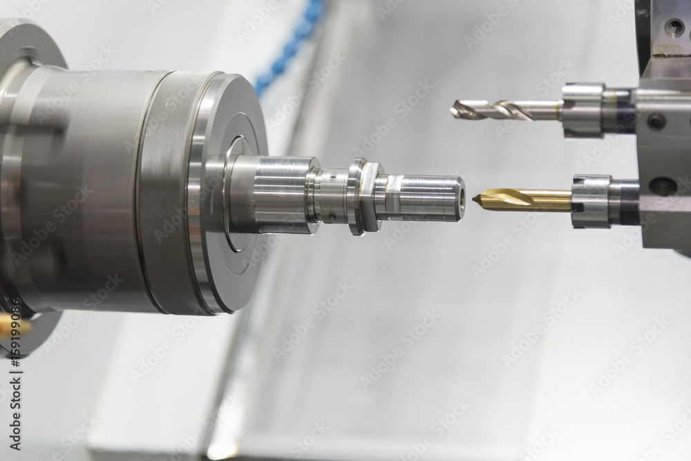 The CNC lathe machine or Turning machine drilling the metal rod with the drill tool and center drill tool .The hi-technology machining concept. The CNC lathe machine or Turning machine drilling the metal rod with the drill tool and center drill tool .The hi-technology machining concept.