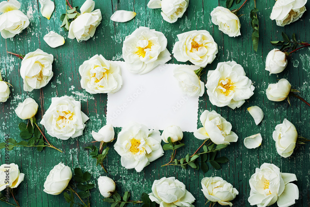 Beautiful rose flowers, green leaves and clean note on teal vintage table top view in flat lay style. Beautiful rose flowers, green leaves and clean note on teal vintage table top view in flat lay style.
