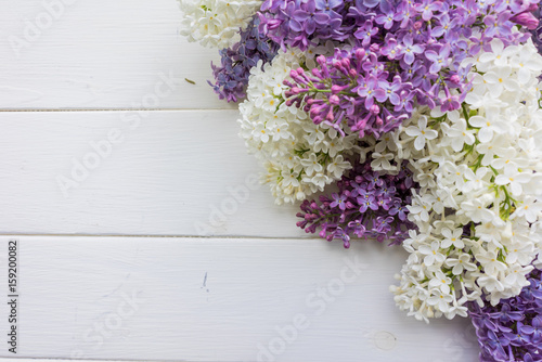 Fototapeta Naklejka Na Ścianę i Meble -  Branch of lilac on a white-painted wooden boards. Top view. Design element for card, banners, print. 