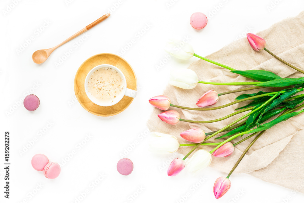 Cup of coffee, lilac and white tulip flowers, macaroon cake on white background. Flat lay, top view Cup of coffee, lilac and white tulip flowers, macaroon cake on white background. Flat lay, top view
