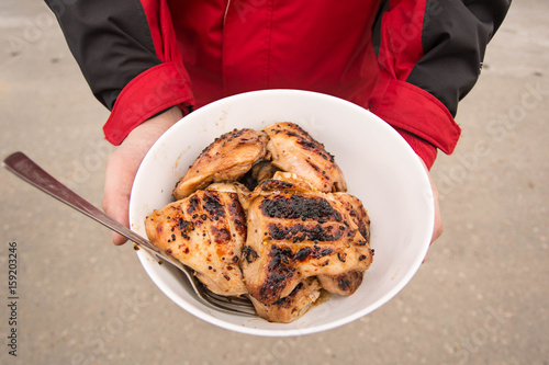 Man holds a plate with grilled chicken in the hands photo